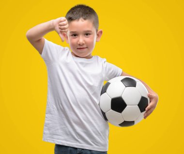 Kızgın yüz, eksi işareti aşağı antipati başparmak ile gösterilen, ret kavramı ile futbol topuyla oynayan koyu saçlı küçük çocuk