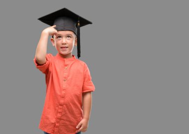 Koyu saçlı küçük çocuk mezuniyet şapkası el ve parmak ile işaret çok mutlu