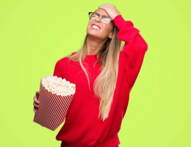 Baş, el ile vurguladı patlamış mısır yemek güzel genç kadın şok utanç ve sürpriz suratla, öfkeli ve sinirli. Korku ve hata için üzgün.