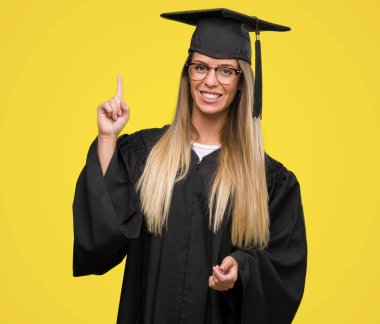 Bir fikir ya da soru işaret parmağı gülen yüz, bir numara ile güzel ve genç birbayan giyen gözlük ve Mezuniyet cübbesi şaşırttı