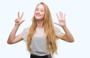 Sarışın genç kadın giyiyor benler gömlek gösterme ve parmakları ile işaret kendinden emin ve mutlu gülümseyerek süre sekiz numara.