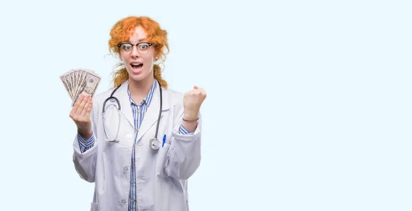 Young Redhead Doctor Woman Holding Dollars Screaming Proud Celebrating Victory — Stock Photo, Image