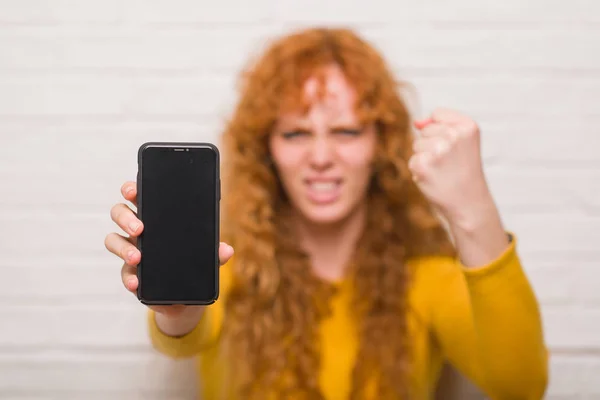 Tuğla Duvar Gösteren Smartphone Üzerinde Oturan Genç Kızıl Saçlı Kadın — Stok fotoğraf