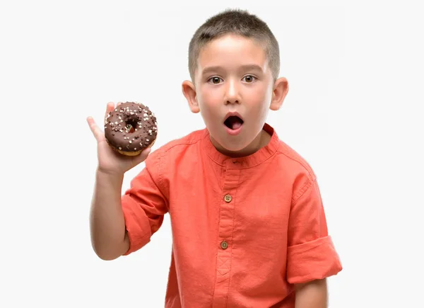 Niño Moreno Comiendo Donut Asustado Shock Con Una Cara Sorpresa — Foto de Stock