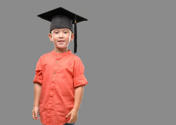 黑发小孩戴着毕业帽带着一张笑脸站着 微笑着露出一丝自信的微笑 — 图库照片