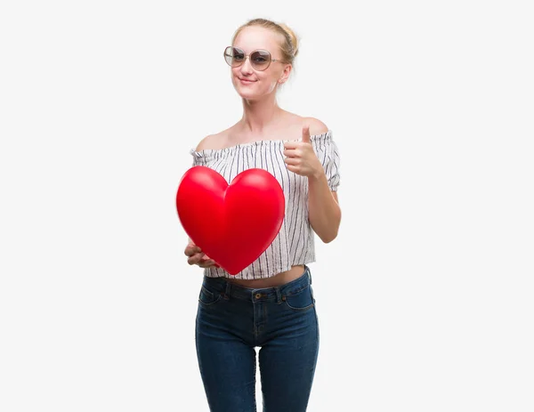 Mulher Adolescente Loira Segurando Coração Vermelho Feliz Com Grande Sorriso — Fotografia de Stock