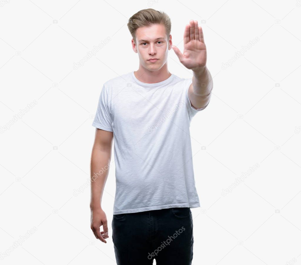 Young handsome blond man with open hand doing stop sign with serious and confident expression, defense gesture
