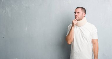 Beyaz delikanlı gri grunge duvar giyen boyun tasması ciddi bir yüz düşünmeye soru, çok karışık bir fikir üzerinde yaralı