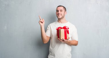 Beyaz delikanlı bir mevcut çok mutlu el ve parmak ile tarafına işaret tutan gri grunge duvarın üzerinden