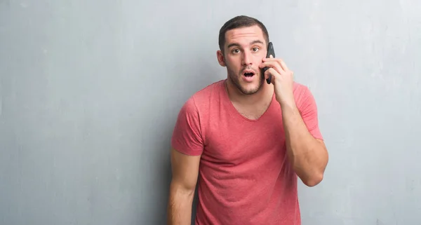 Young Caucasian Man Grey Grunge Wall Talking Phone Scared Shock — Stock Photo, Image