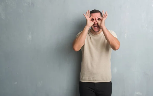 Kaukasische Jongeman Grijs Grunge Muur Doen Gebaar Als Verrekijker Steken — Stockfoto