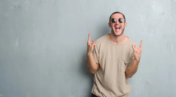 Homem Caucasiano Jovem Sobre Parede Grunge Cinza Usando Óculos Sol — Fotografia de Stock