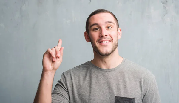 Joven Caucásico Hombre Sobre Gris Grunge Pared Sorprendido Con Una —  Fotos de Stock