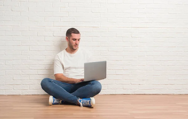 Καυκάσιος Νεαρός Κάθεται Πάνω Από Λευκό Τοίχο Χρησιμοποιώντας Φορητό Υπολογιστή — Φωτογραφία Αρχείου