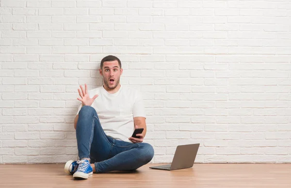 Joven Hombre Caucásico Sentado Sobre Pared Ladrillo Blanco Usando Computadora — Foto de Stock