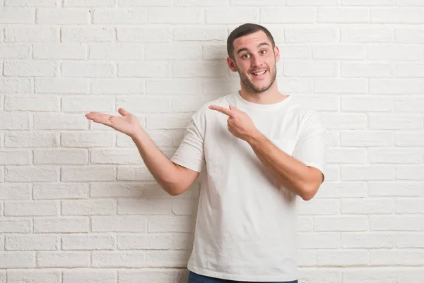 Joven Hombre Caucásico Pie Sobre Pared Ladrillo Blanco Sorprendido Sonriendo — Foto de Stock