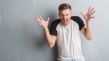 Genç Kızıl saçlı adam kızgın ve silah ile başarı için deli duvar gri grunge kutluyor üzerinden kaldırdı ve heyecanlı çığlık gözler kapalı. Kazanan kavramı