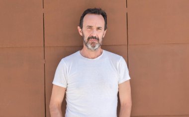 Yakışıklı üst düzey adam akıllı yüzünde ciddi düşünme emin bir ifade ile duvarın üzerinden ayakta