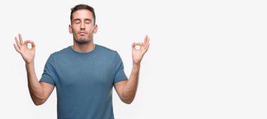 Yakışıklı genç Casual adam sakin ol ve gülümseyen gözlerle parmak ile meditasyon jest yapıyor kapalı. Yoga kavramı.