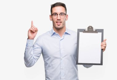 Yakışıklı genç iş adamı bir pano sürpriz bir fikir ya da soru işaret parmağı ile gülen yüz, gösterilen bir numara