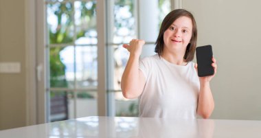 Down sendromu kadın evde işaret ve başparmak kadar mutlu yüz gülümseyen tarafı ile gösterilen smartphone kullanarak