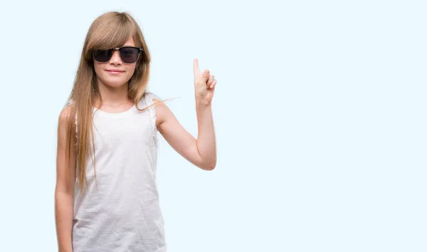 Young Blonde Toddler Wearing Sunglasses Surprised Idea Question Pointing Finger — Stock Photo, Image