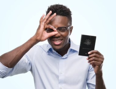 Avustralya pasaportu ile ok işareti ile el parmaklarının arasından seyir göze yapıyor gülümseyen mutlu yüz tutan genç Afro-Amerikan adam