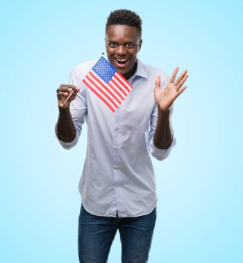 Çok mutlu ve heyecanlı, kazanan ifade büyük gülümseme ile çığlık zaferini kutluyor ABD bayrağı tutarak ve ellerini kaldırdı genç Afro-Amerikan adam