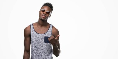 El ve parmak ile yukarı dönük mutlu yüz ile gülümseyen güneş gözlüğü takmış genç Afro-Amerikan adam