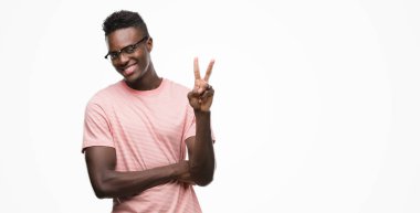 Mutlu yüz zafer işareti yaparken kameraya göz kırpıyor ile pembe gömlek gülümseyen giyen genç Afro-Amerikan adam. İki numaralı.