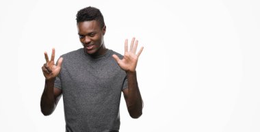 Gri t-shirt gösterme ve parmakları ile işaret giyen genç Afro-Amerikan adam kendinden emin ve mutlu gülümseyerek süre sekiz numara.