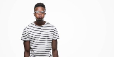 Gözlük ve lacivert t-shirt şişirme yanakları komik surat ile giyen genç Afro-Amerikan adam. Ağız ile hava, deli ifade şişirilmiş.