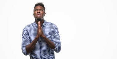 Yalvarıyor ve umut ifade yüzünde çok duygusal ve endişe ile birlikte elleriyle dua mavi gömlek giymiş genç Afro-Amerikan adam. Bağışlanmak. Din kavramı.