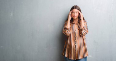 Genç esmer kadın yüzünden grunge gri duvar baş baş ağrısı için el ile çünkü stres. Migren muzdarip.