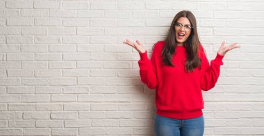 Beyaz tuğla duvar kaldırdı kollarını açarak deli ve başarı için hayran kutluyor ve açık gözleri heyecanlı çığlık üzerinde duran genç esmer kadın. Kazanan kavramı