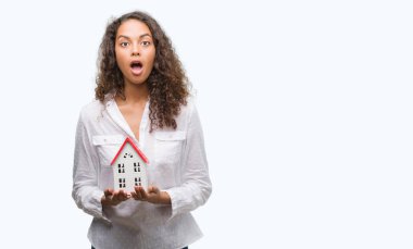 Genç İspanyol gerçek durum Aracısı kadın holding küçük ev bir sürpriz yüz, korkuyor ve heyecanlı korku ifadesi ile şok korkmuş