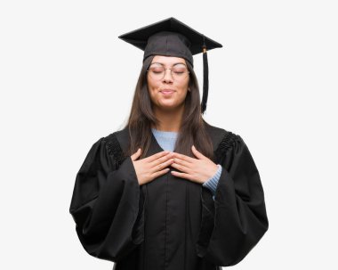 Giyen genç İspanyol kadın kap mezun oldu ve kapalı gözler ve yüzünde minnettar jest ile göğüs üzerinde üniforma ile gülümseyen eller. Sağlık kavramı.