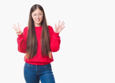 İzole arka plan ve kendinden emin ve mutlu gülümseyerek süre sekiz parmak numara ile yukarıyı gösteren gözlük takan Genç Çinli kadın.