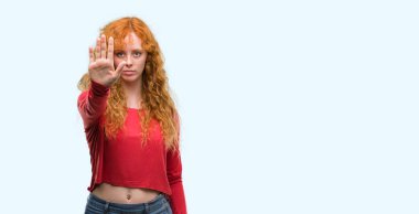 Genç Kızıl saçlı kadın açık eliyle dur işareti ile ciddi ve kendine güvenen ifade, savunma hareketi yapıyor