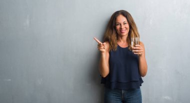 Orta yaş İspanyol kadın el ve parmak ile tarafına işaret çok mutlu su bardak içme