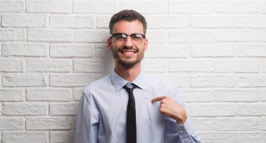 Sürpriz yüz işaret parmağı beyaz tuğla duvarın üzerinden kendisine duran genç yetişkin iş adamı