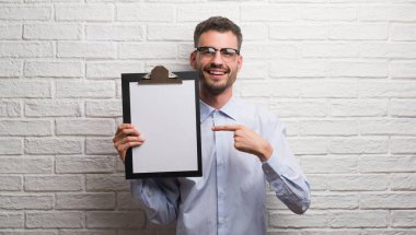 Genç Yetişkin iş adamı Pano çok mutlu el ve parmak ile işaret tutan tuğla duvarın üzerinden