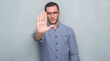 Genç beyaz iş adamı açık eliyle dur işareti ile ciddi ve kendine güvenen ifade, savunma jest yapıyor gri grunge duvarın üzerinden