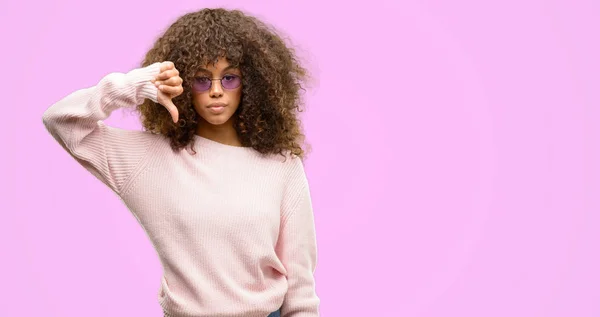 アフリカ系アメリカ人の女性が怒っている顔 ダウン親指で嫌悪感を示すマイナス記号 拒絶反応の概念とピンクのセーターを着て — ストック写真