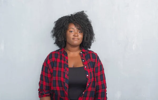 年轻的非洲裔美国人时髦的女人在灰色的垃圾墙上表情严肃 简单而自然地看着相机 — 图库照片
