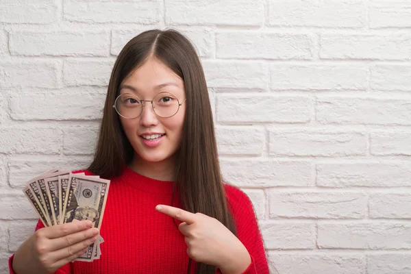 Jovem Chinesa Sobre Parede Tijolo Segurando Dólares Muito Feliz Apontando — Fotografia de Stock