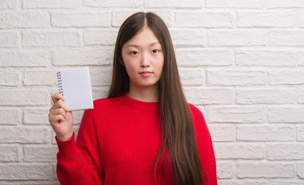 Joven Mujer China Sobre Pared Ladrillo Mostrando Cuaderno Blanco Con —  Fotos de Stock