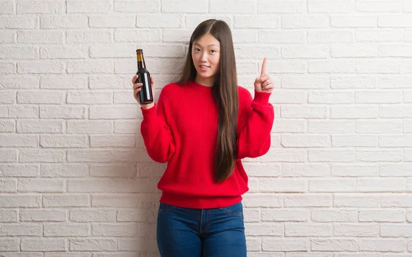 Joven Mujer China Sobre Pared Ladrillo Bebiendo Cerveza Sorprendida Con — Foto de Stock