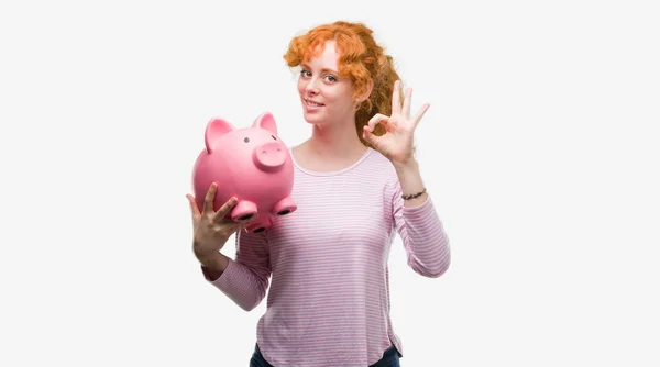 Junge Rothaarige Frau Hält Sparschwein Tut Zeichen Mit Fingern Ausgezeichnetes — Stockfoto