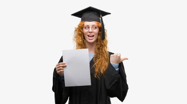 Joven Pelirroja Vistiendo Uniforme Graduado Sosteniendo Grado Señalando Mostrando Con — Foto de Stock